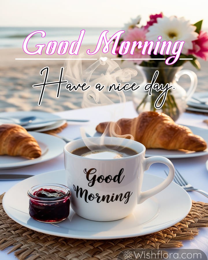 Good Morning Images featuring a serene seaside breakfast with a steaming mug, croissants, berry jam, daisies, and the soft glow of the morning sun over gentle ocean waves, perfect for peaceful good morning blessings.